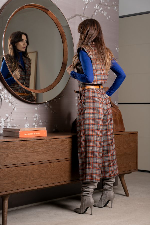 Chaleco de invierno corto, con hombreras, y detalles de botones dorados y un largo ideal para usar con pantalones de cintura alta, hecho de lana a cuadros estilo escocés azul y naranja.