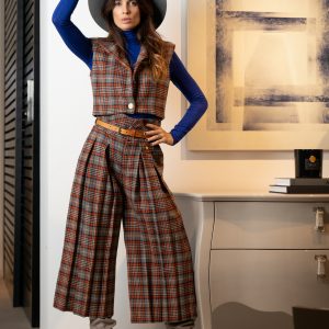 Chaleco de invierno corto, con hombreras, y detalles de botones dorados y un largo ideal para usar con pantalones de cintura alta, hecho de lana a cuadros estilo escocés azul y naranja.
